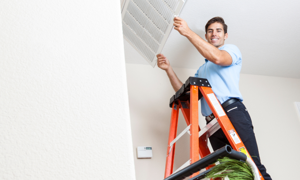 Air conditioning duct cleaning technician reattaching a vent to the ceiling